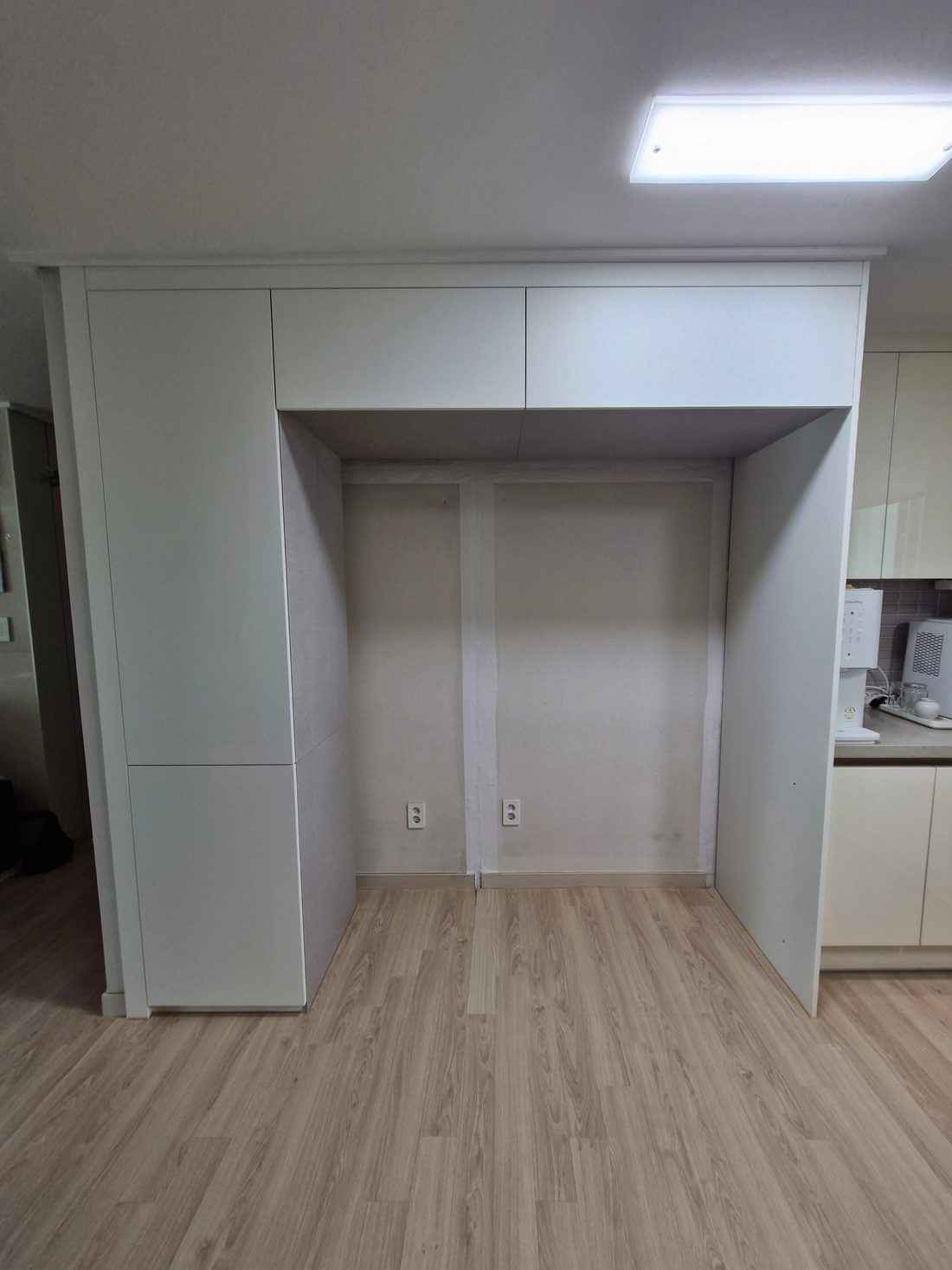 도어 설치 전 벽면과 배관 위치가 드러난 냉장고장 골조 단계, 콘센트 위치가 표시된 현장